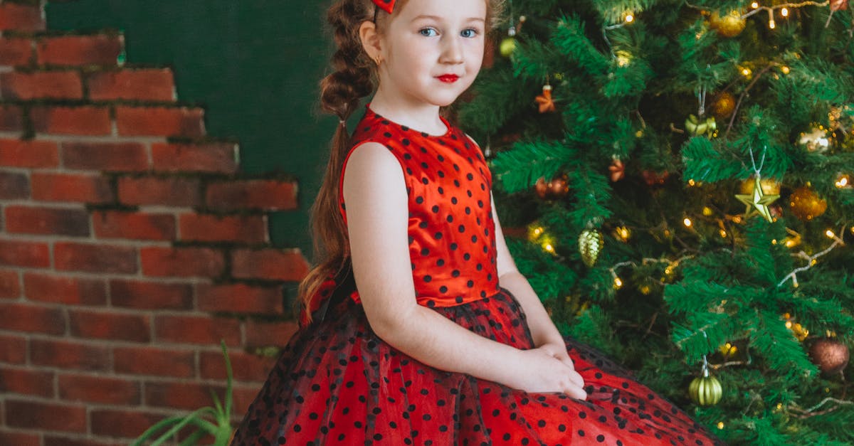 A little girl standing in front of a brick wall