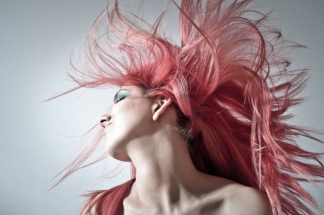 A close up of a woman with pink hair taking a selfie